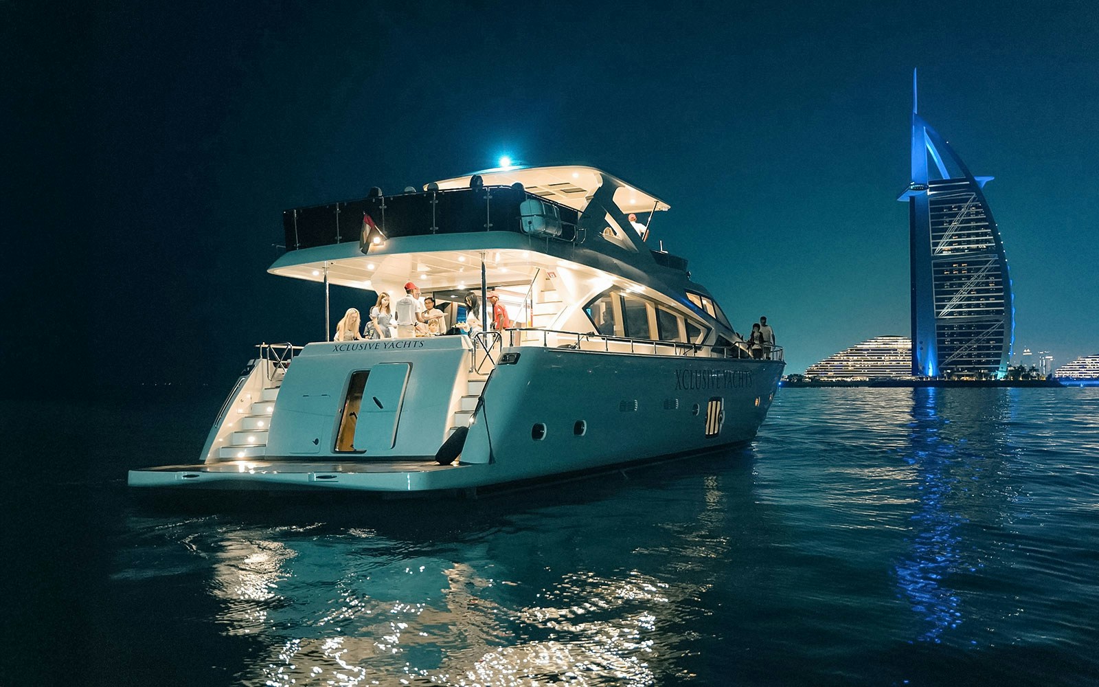 Luxury yacht cruising near Burj Al Arab in Dubai Marina with guests enjoying a BBQ lunch.