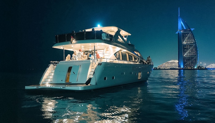 Luxury yacht cruise at night near Burj Al Arab, Dubai.