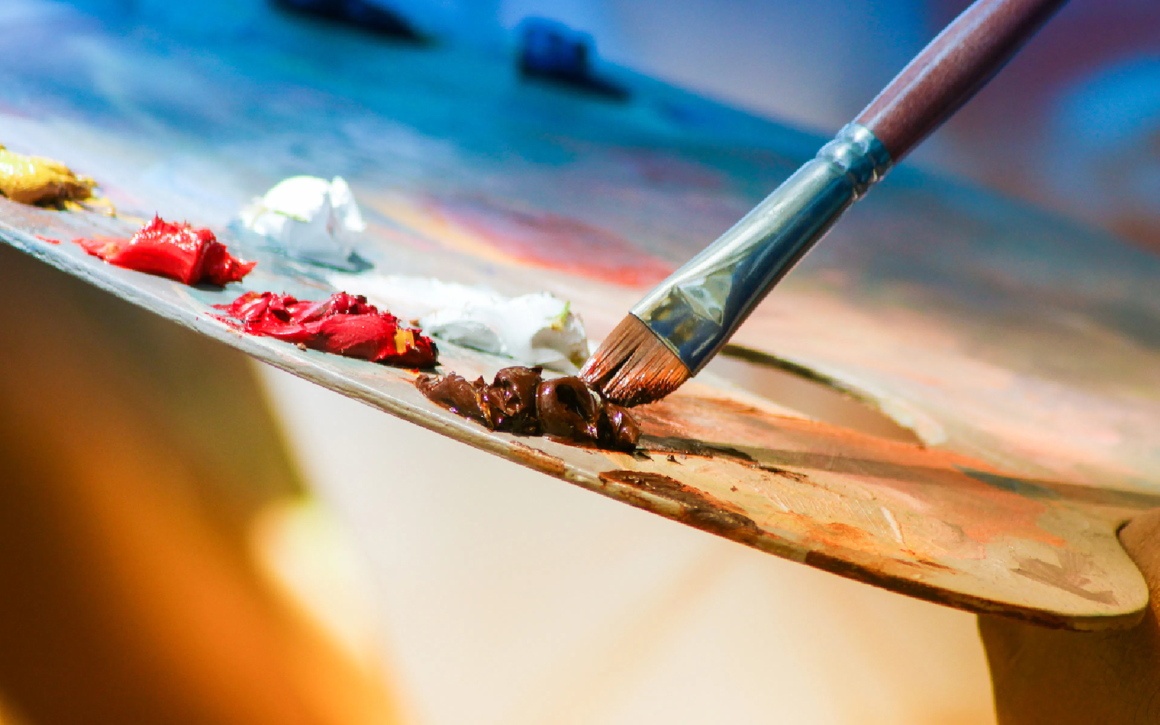 Paintbrush mixing colors on an artist's palette in shallow focus.