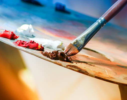 Paintbrush mixing colors on an artist's palette in shallow focus.