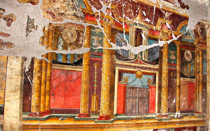 Ancient fresco with ornate columns in Pompeii, Italy, part of Artecard Campania tour.