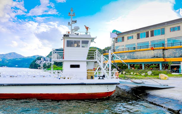 Ferry docked at Nami Island with mountains and buildings in the background, part of Seoul day tour.