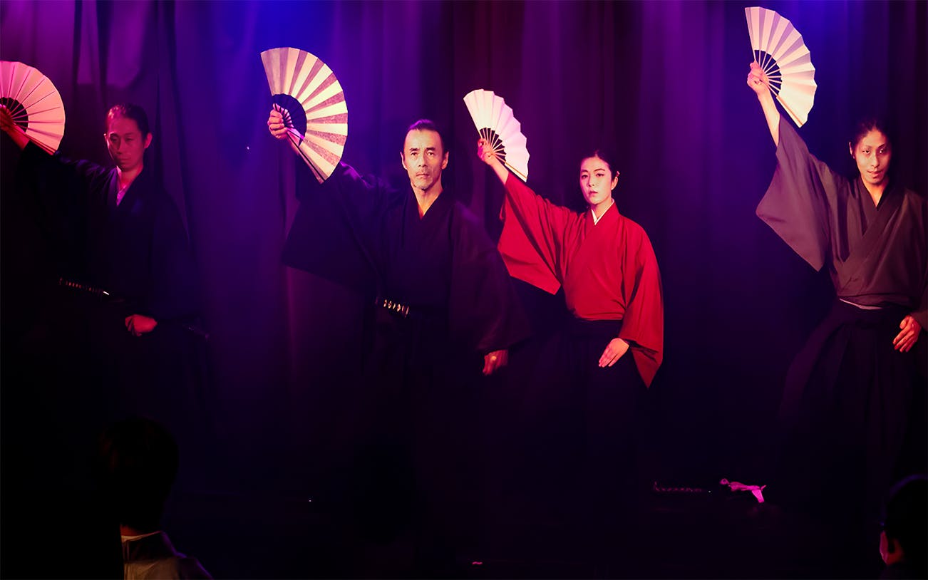 Performers in traditional attire with fans at Samurai Performance Show.