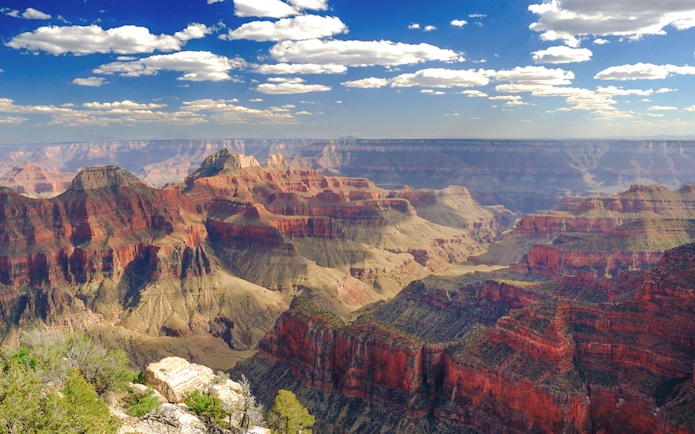 Grand Canyon panoramic view with layered rock formations under a blue sky.