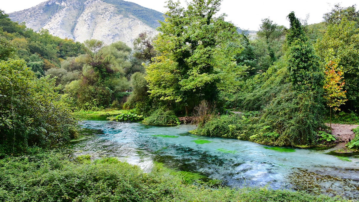 Blue Eye spring surrounded by lush greenery and mountains in Albania.