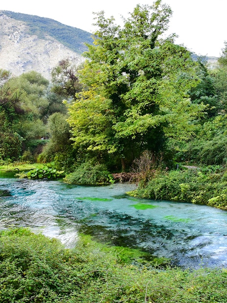 Blue Eye spring surrounded by lush greenery and mountains in Albania.