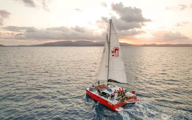 Sailing catamaran on Tongarra Sail Day Tour at sunset, Whitsunday Islands.