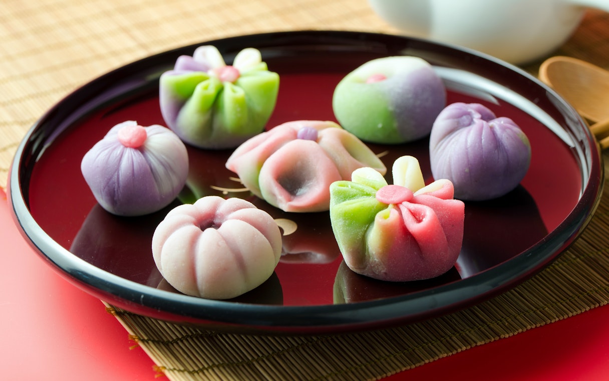 Assorted colorful wagashi on a black plate, showcasing traditional Japanese sweets.