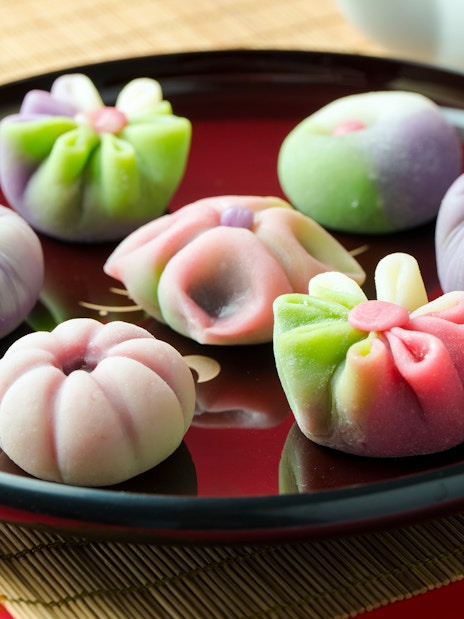 Assorted colorful wagashi on a black plate, showcasing traditional Japanese sweets.