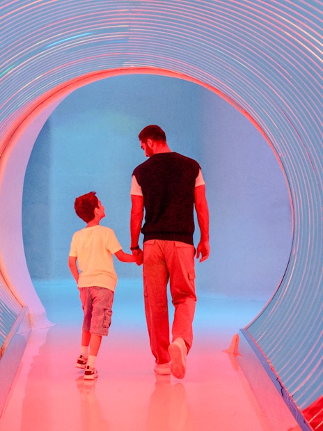 Man and child walking through a colorful tunnel at AYA Universe, Dubai.