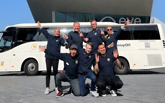 Tour guides posing in front of a bus for roundtrip transfers from Amsterdam to Zaanse Schans.