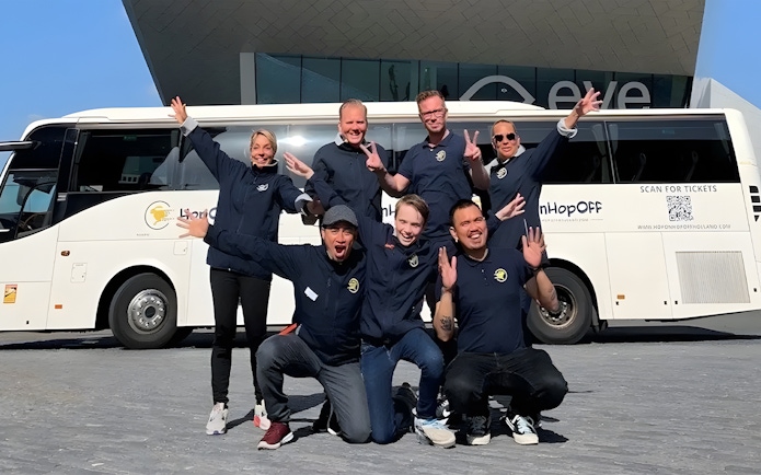 Tour guides posing in front of a bus for roundtrip transfers from Amsterdam to Zaanse Schans.