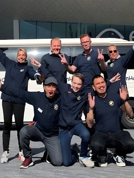 Tour guides posing in front of a bus for roundtrip transfers from Amsterdam to Zaanse Schans.