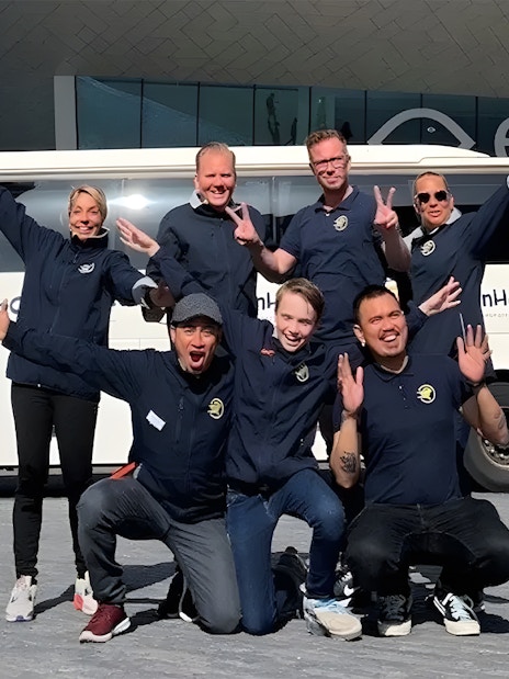 Tour guides posing in front of a bus for roundtrip transfers from Amsterdam to Zaanse Schans.