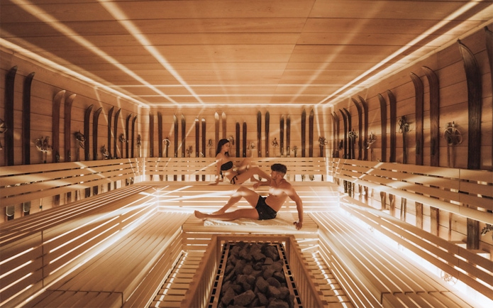 Visitors relaxing in a wooden sauna at QC Terme Chamonix Resort & Spa.