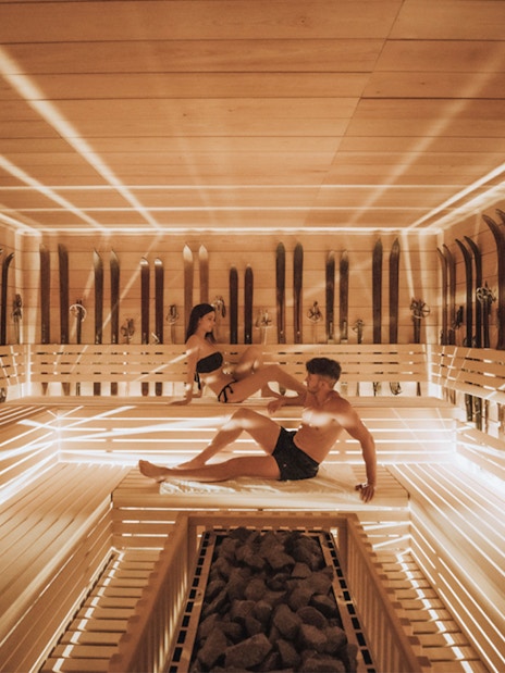 Visitors relaxing in a wooden sauna at QC Terme Chamonix Resort & Spa.