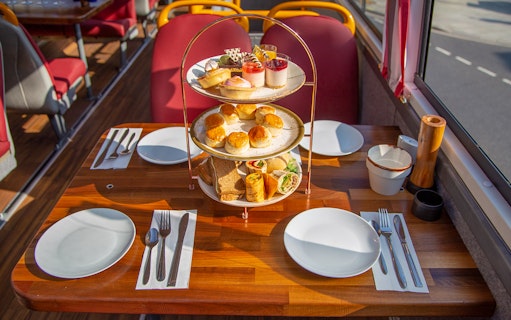 Afternoon tea setup with pastries and sandwiches on a bus table.