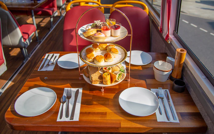 Afternoon tea setup with pastries and sandwiches on a bus table.