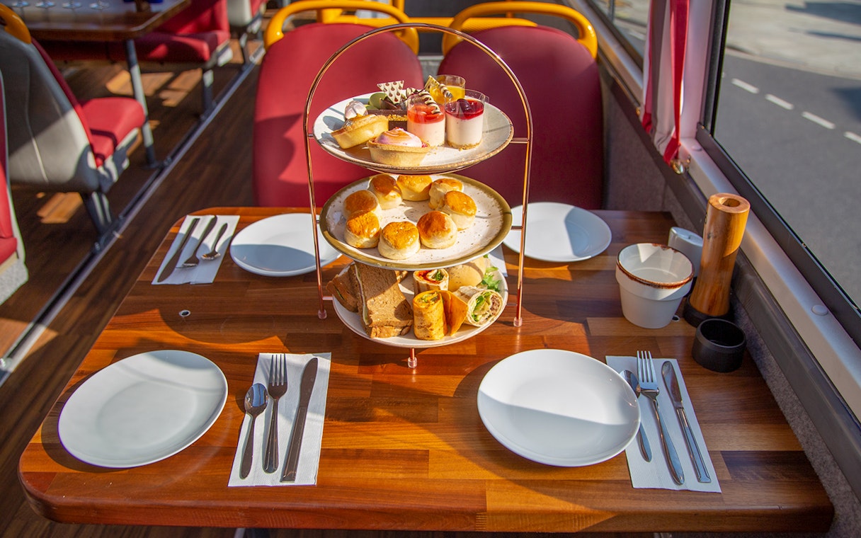 Afternoon tea setup with pastries and sandwiches on a bus table.
