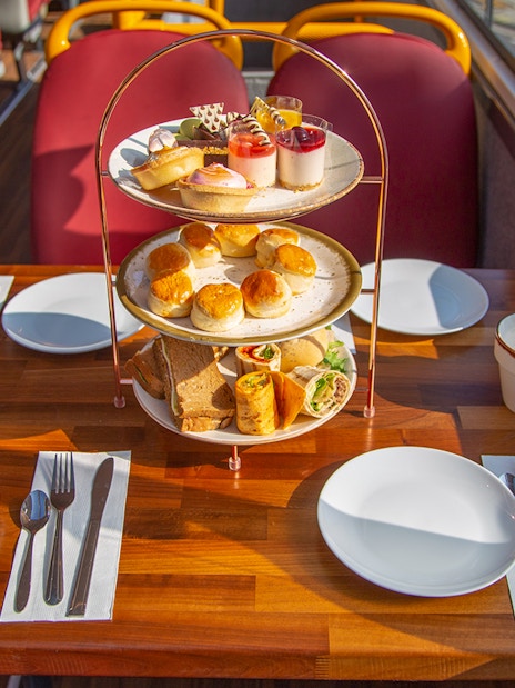Afternoon tea setup with pastries and sandwiches on a bus table.