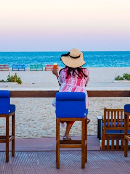 Woman enjoying a drink at Al Majles Resort beachside, overlooking the ocean.