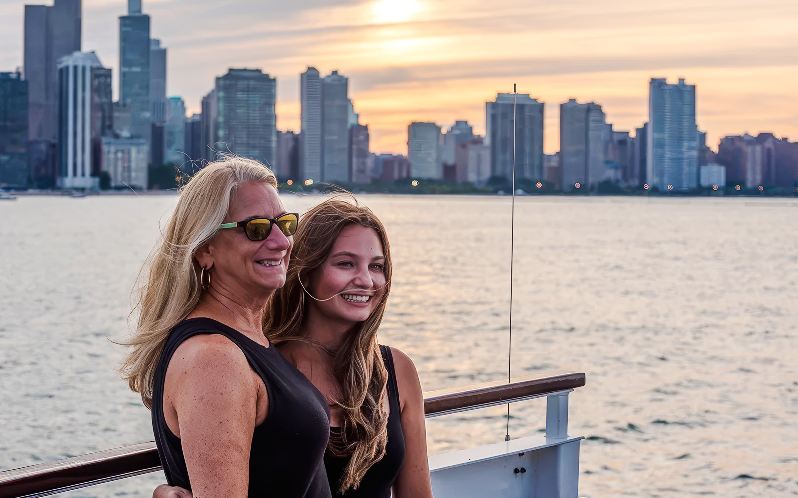 Two people enjoying a sunset cruise with the Chicago skyline in the background.