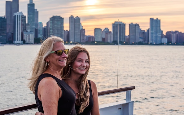 Two people enjoying a sunset cruise with the Chicago skyline in the background.
