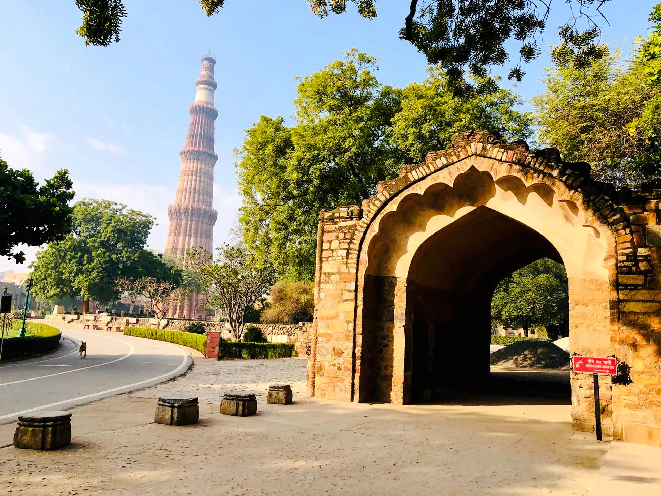 Qutub Minar and stone archway in Delhi, India, on a sunny day.