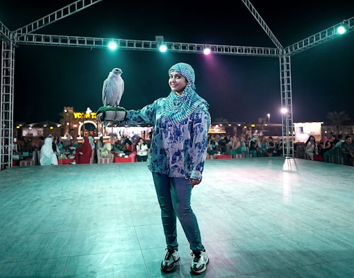 Lady holding a falcon during a Dubai desert safari experience.