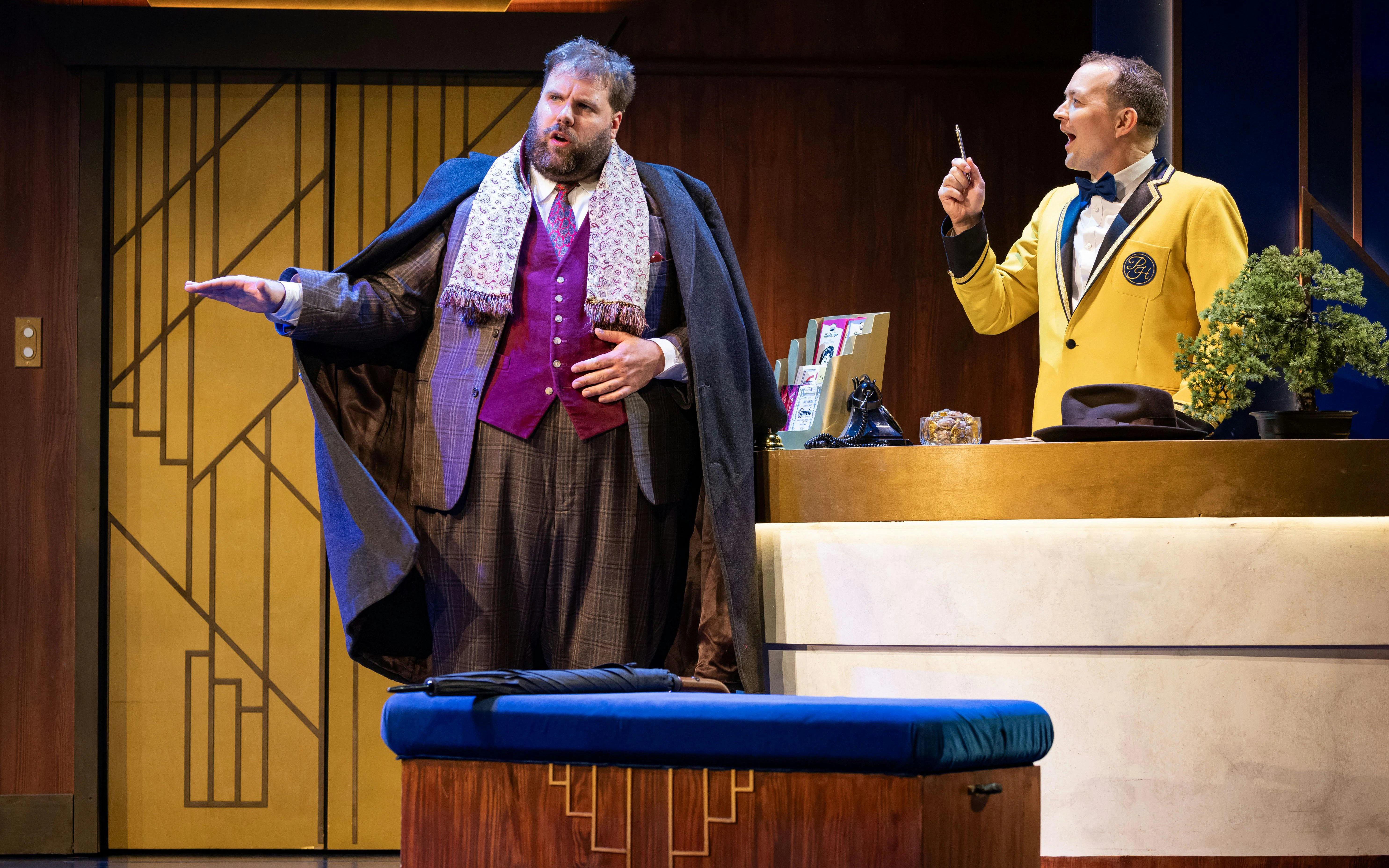 Actors performing a scene from "The Comedy About Spies" in a hotel lobby setting.