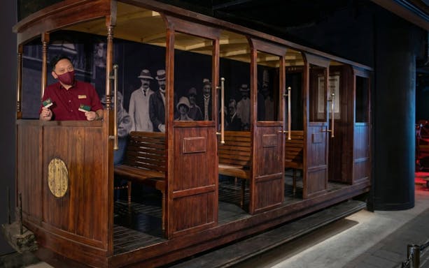 Peak Tram conductor holding tickets inside vintage tram car, Hong Kong.