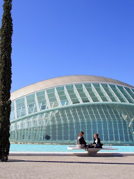 People sitting by the Hemisfèric building at City of Arts and Sciences, Valencia.