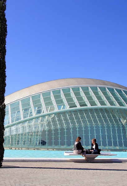 People sitting by the Hemisfèric building at City of Arts and Sciences, Valencia.