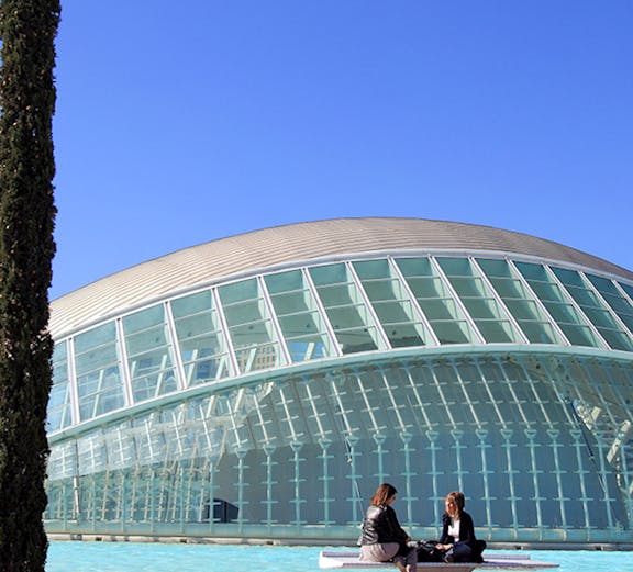 People sitting by the Hemisfèric building at City of Arts and Sciences, Valencia.