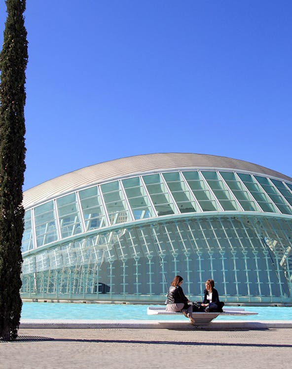 People sitting by the Hemisfèric building at City of Arts and Sciences, Valencia.