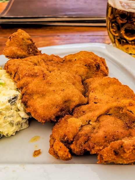 Wiener Schnitzel with potato salad and beer on a wooden table.