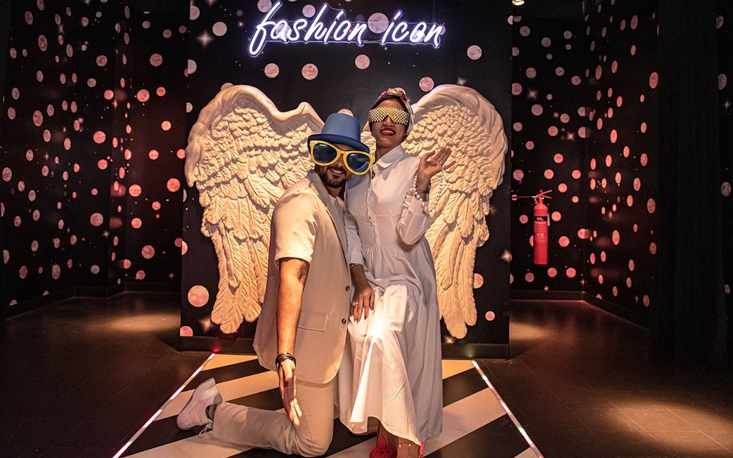 Visitors posing with angel wings at Madame Tussauds Dubai fashion icon exhibit.