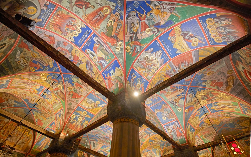 Colorful frescoes on the ceiling of a Meteora monastery, Greece, depicting religious scenes.