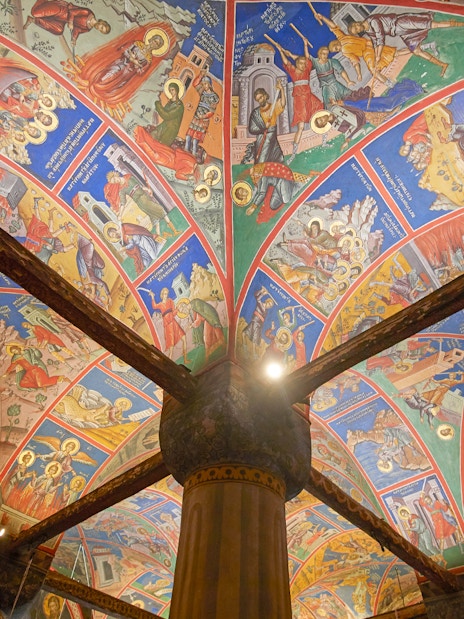 Colorful frescoes on the ceiling of a Meteora monastery, Greece, depicting religious scenes.