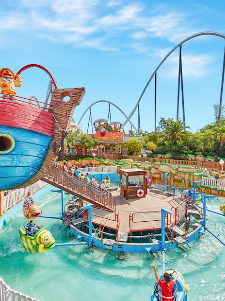 Colorful boat ride at PortAventura Park with roller coaster in background.