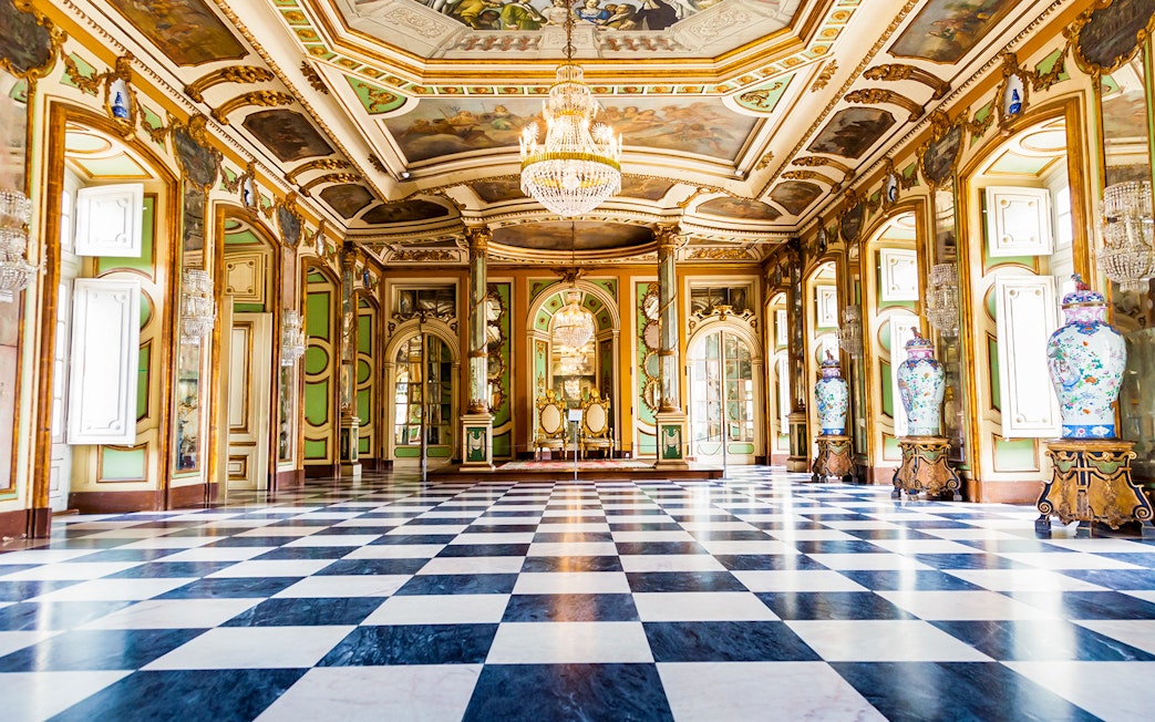 Hall of Ambassadors in Queluz National Palace with ornate decor and chandeliers.