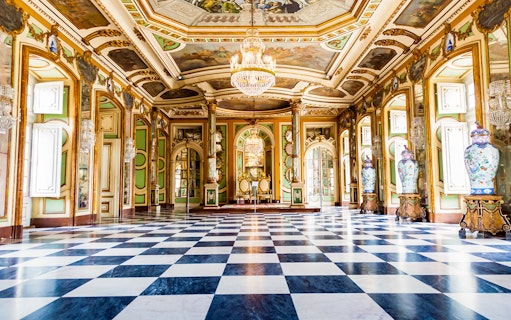 Hall of Ambassadors in Queluz National Palace with ornate decor and chandeliers.