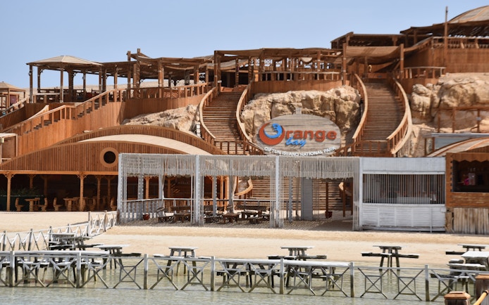 Orange Bay entrance with wooden structures and seating area, Red Sea near Hurghada, Egypt.