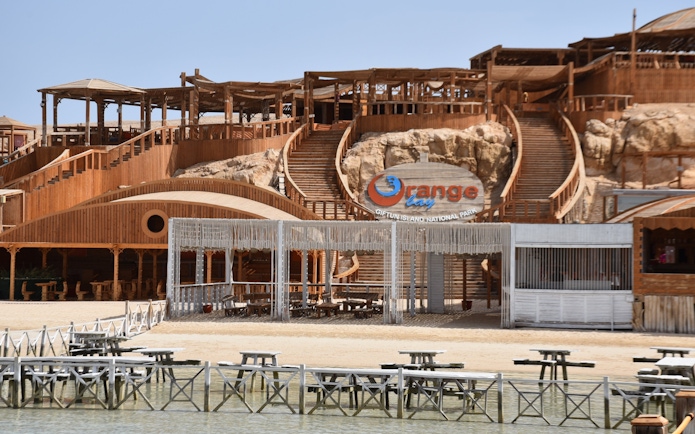 Orange Bay entrance with wooden structures and seating area, Red Sea near Hurghada, Egypt.
