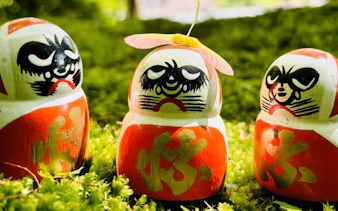 Kachi Daruma dolls on a mossy shelf at Katsuo-ji Temple, Japan.