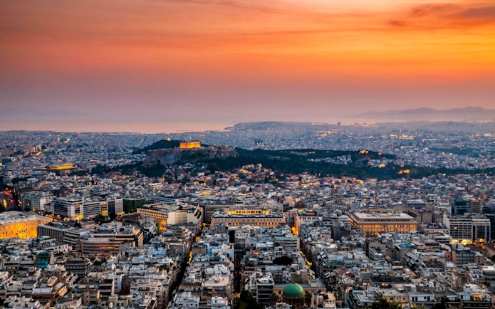 Acropolis and Parthenon at sunset, overlooking Athens cityscape.