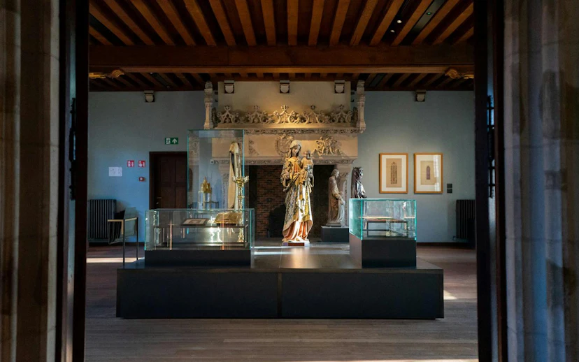 Gruuthusemuseum interior with historical artifacts and sculptures on display.
