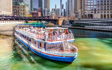 Tour boat on Chicago River with city skyline and bridge in background.