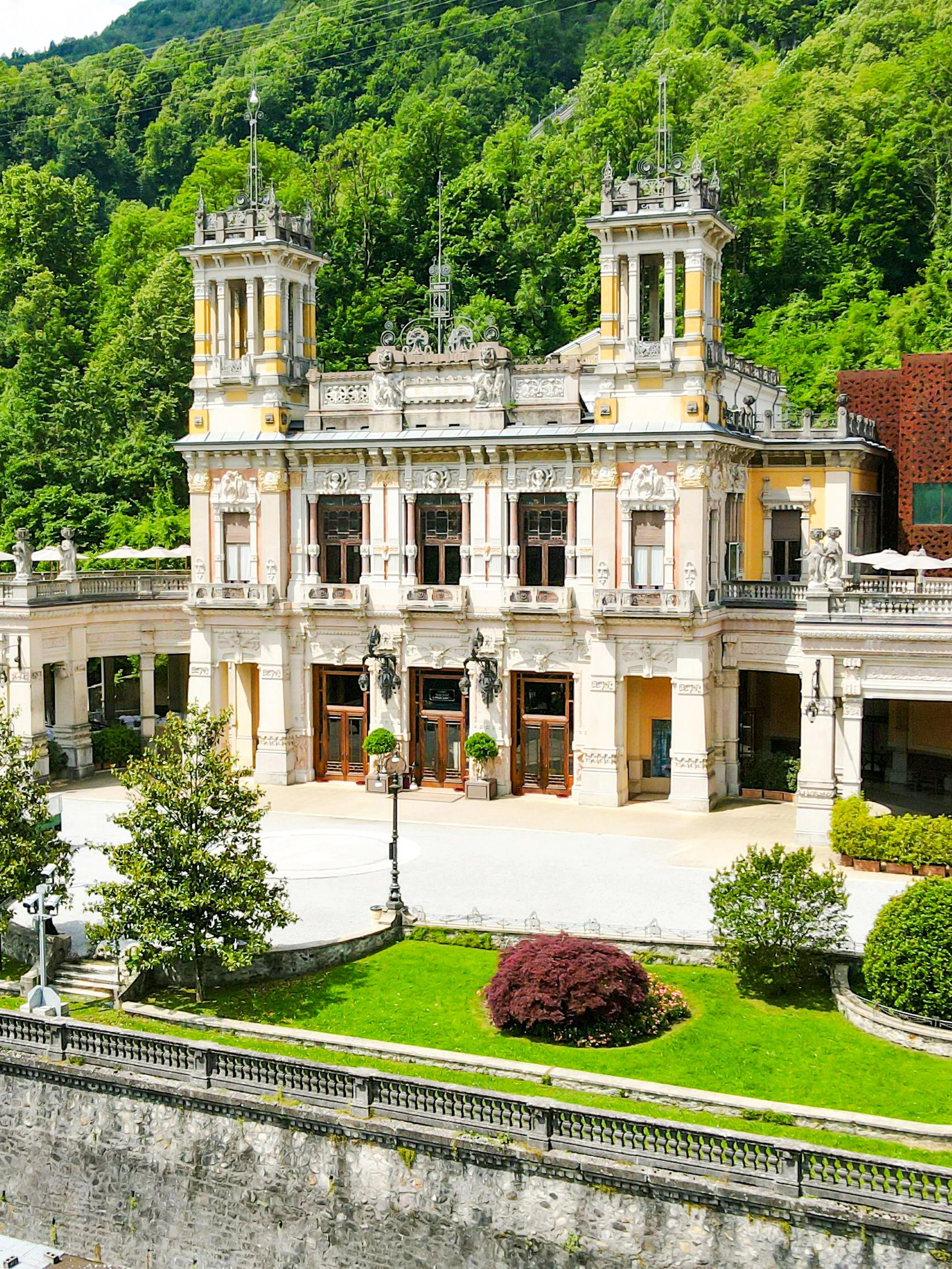 Historic QC Terme San Pellegrino Spa building surrounded by lush greenery in Italy.