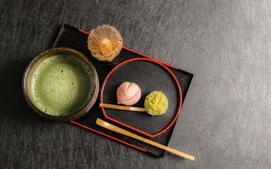 Wagashi sweets with a bowl of matcha tea on a black tray.